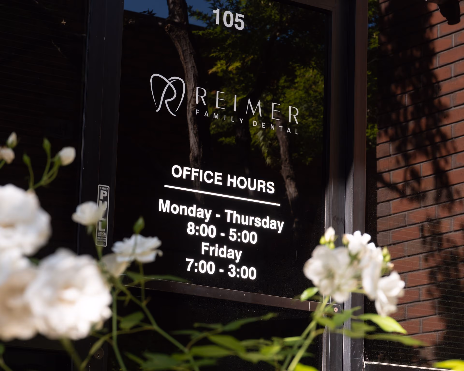 Glass door of Reimer Family Dental showing office hours Monday-Thursday 8 to 5, Friday 7 to 3.