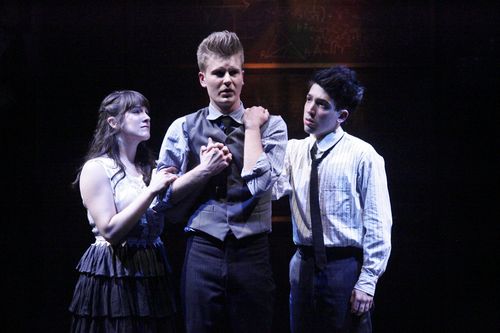 Production photo from Spring Awakening showing three young characters in an intimate moment onstage.