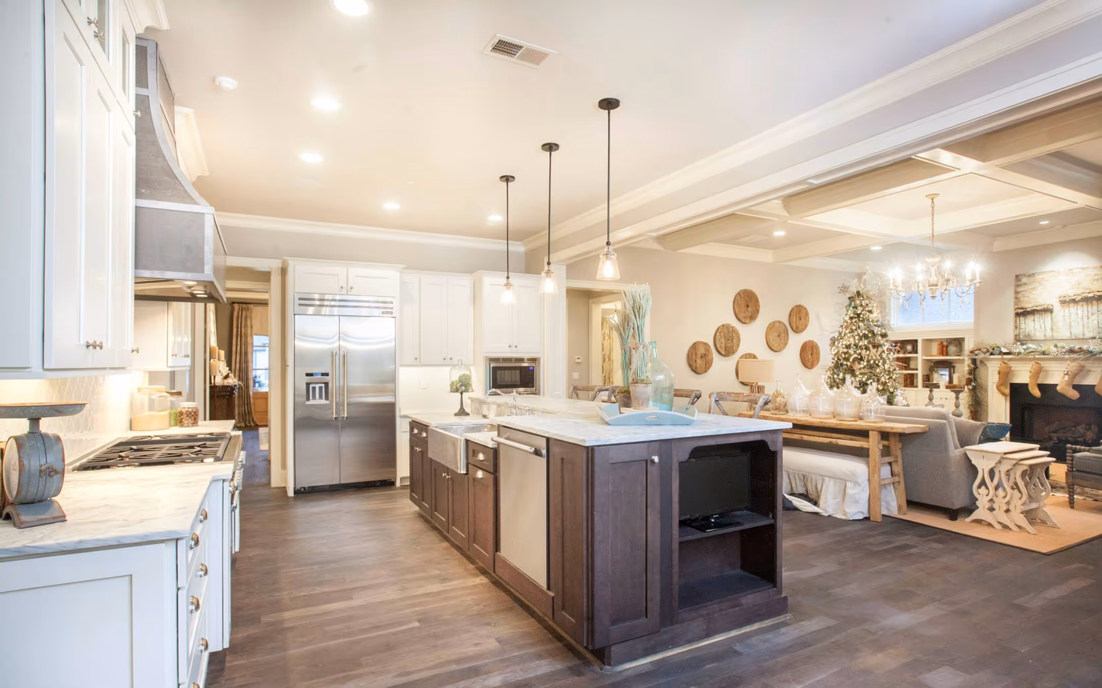 Bright modern kitchen with dark wood island, stainless appliances, and a living room with Christmas decor.