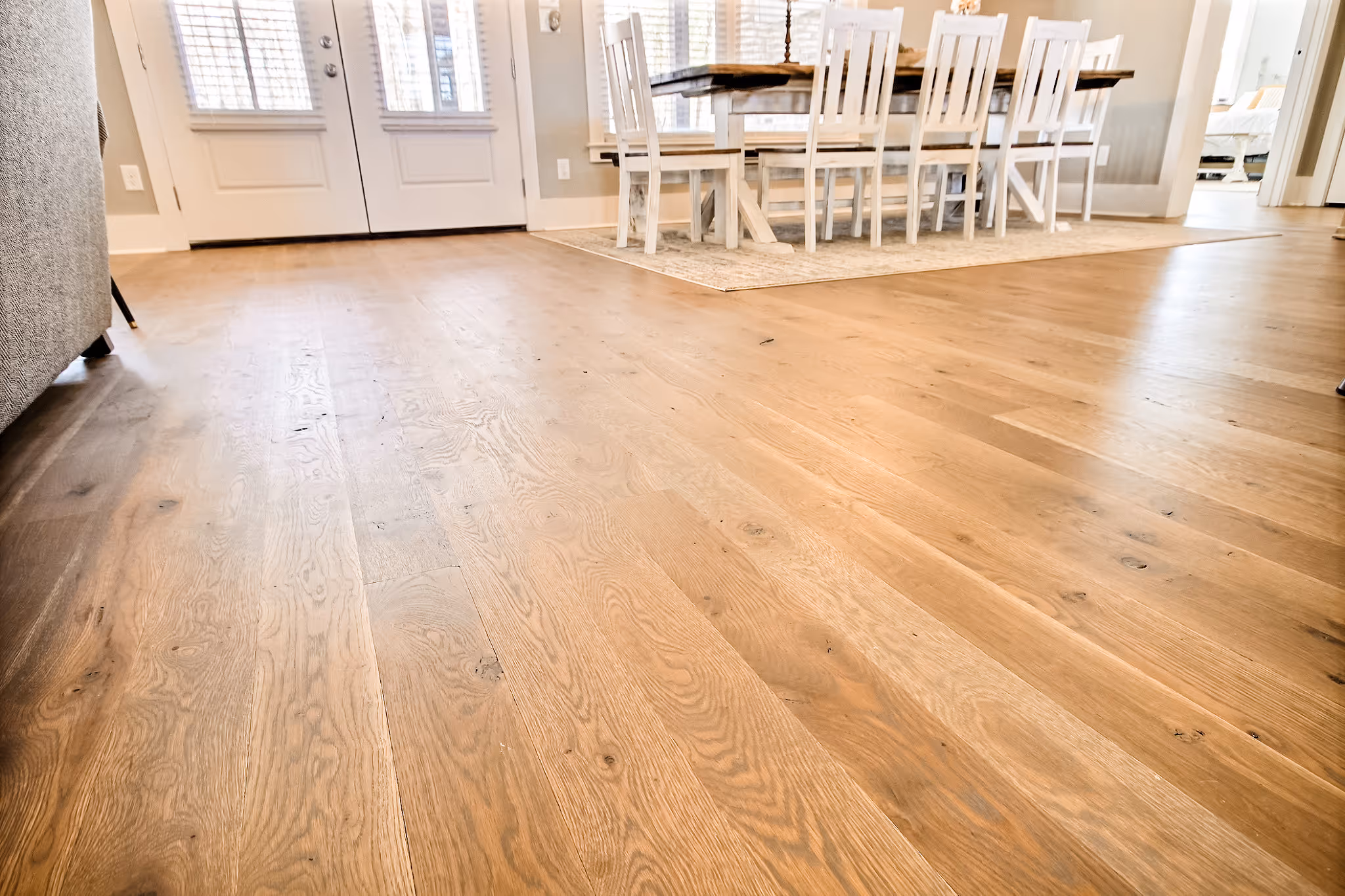 Open dining area with light hardwood floors and white wooden chairs around a table.