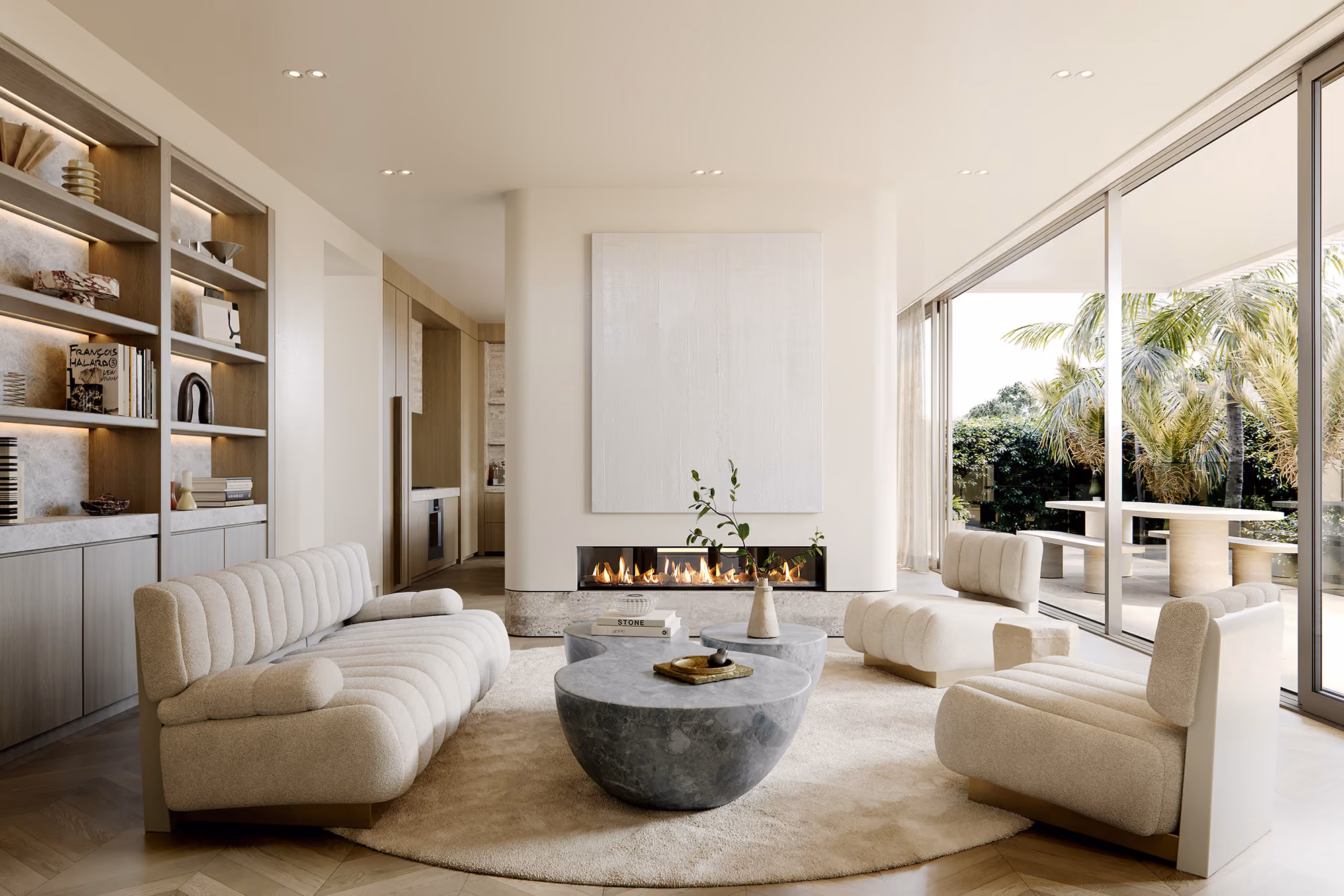 Open-plan living room at 5 Clarendon Road with bouclé sofas, travertine coffee tables and gas fireplace opening to outdoor dining
