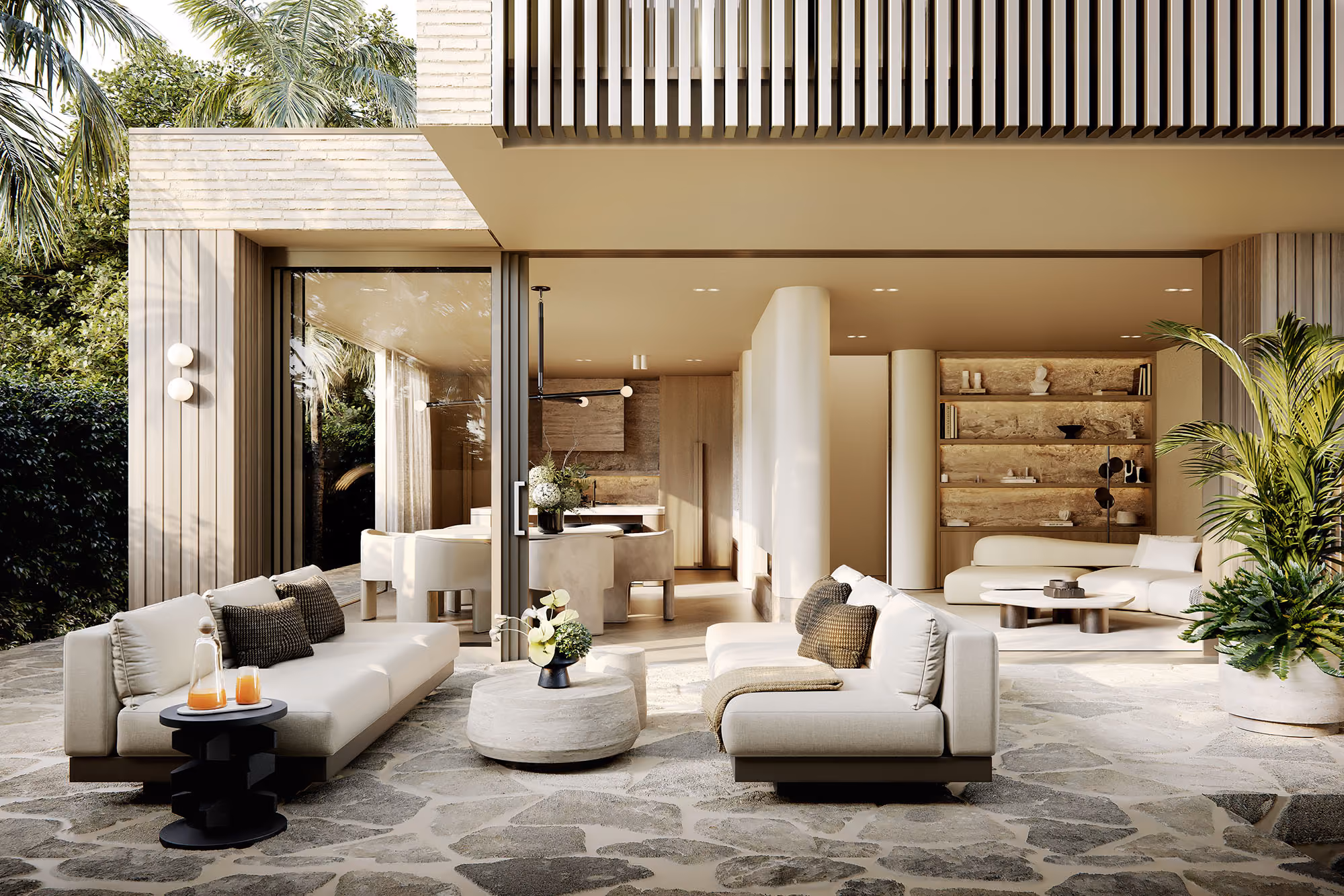 Indoor-outdoor living space at St Heliers residence with stone terrace, built-in shelving and seamless glass sliding doors