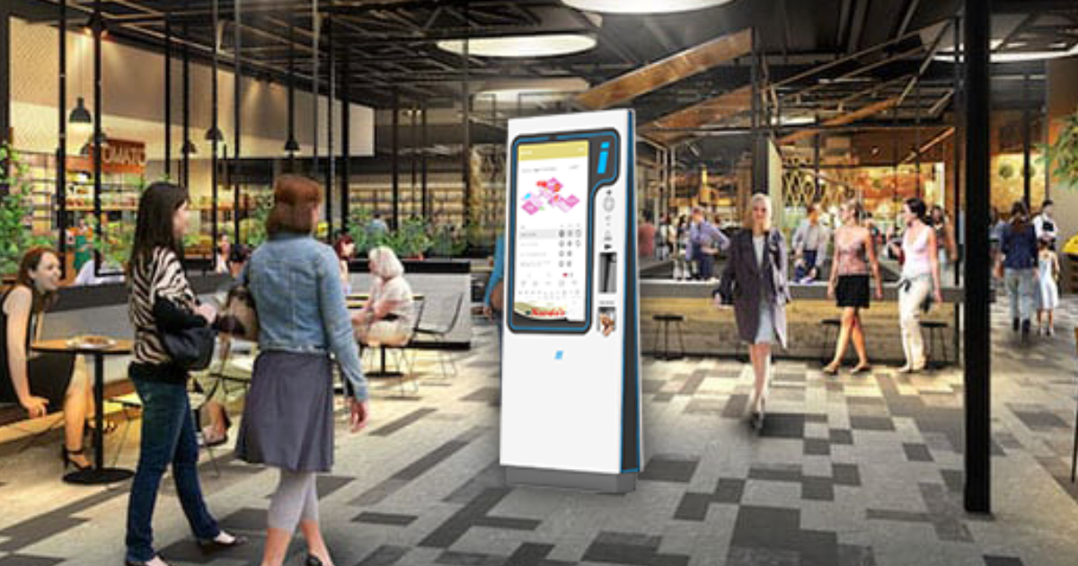 Indoor shopping mall scene featuring people walking and sitting in a food court area, with a digital wayfinding kiosk prominently displayed in the center of the image.