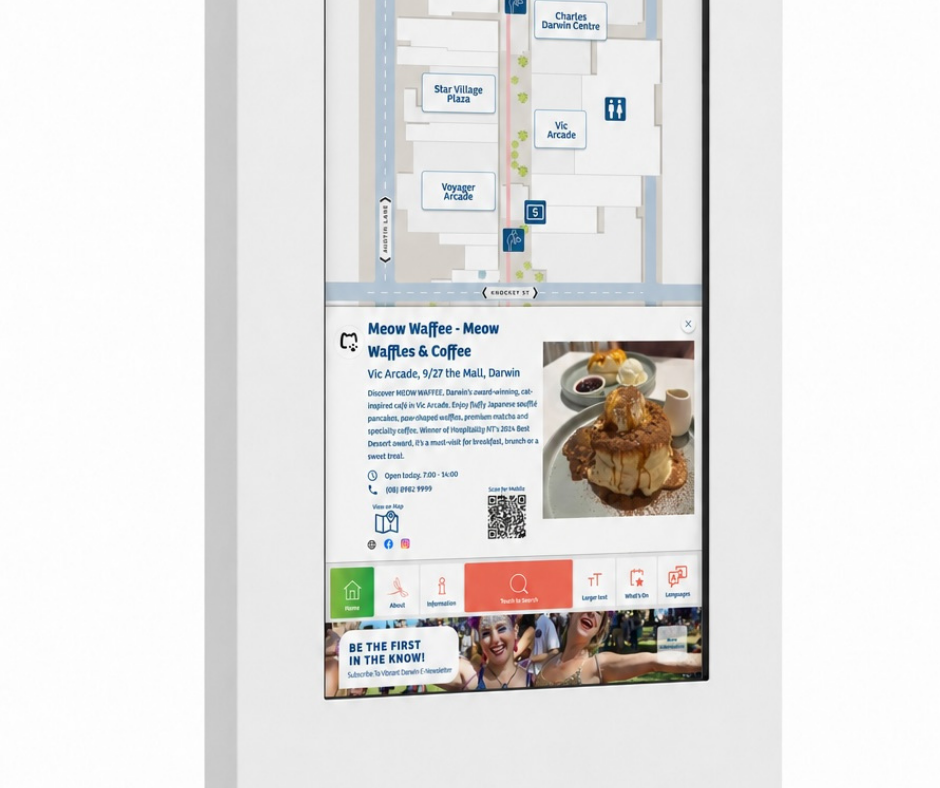 Digital kiosk screen showing a map of a nearby area with locations including Star Village Plaza and Charles Darwin Centre, and detailed information about 'Meow Waffee - Meow Waffles & Coffee' at Vic Arcade, featuring an image of a dessert waffle with syrup, cream, and sauces, operating hours, contact info, QR code, and navigation icons for Home, About, Information, Search, Larger Text, What’s On, and Languages.