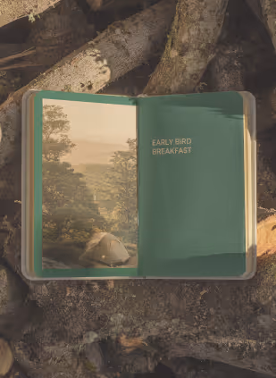 Open book on tree bark with a nature photo and text that reads 'EARLY BIRD BREAKFAST'.