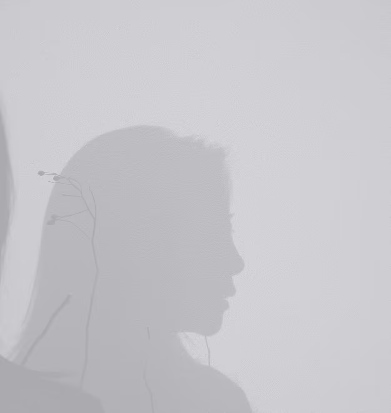 Shadow profile of a person with long hair and earphones against a plain light background.