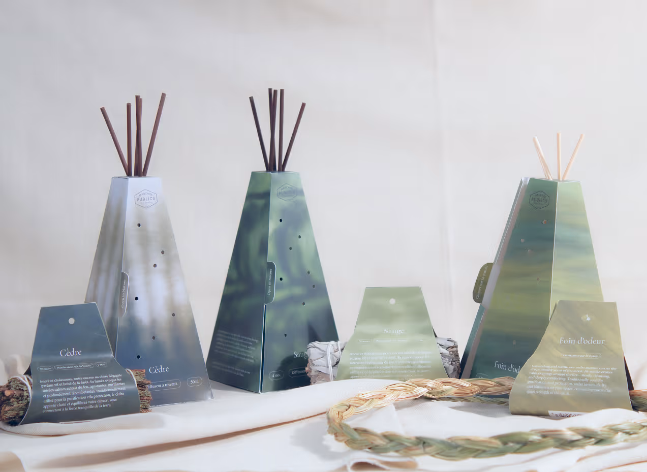 Three pyramid-shaped reed diffusers with sticks and their labeled fragrance packages on a white fabric surface.