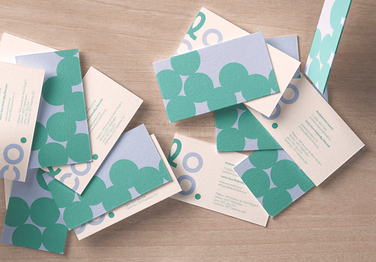 Scattered business cards with green and blue circular patterns on a wooden surface.