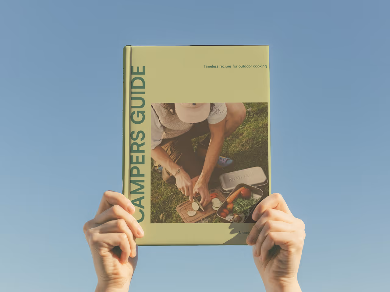 Hands holding a book titled 'Campers Guide'.
