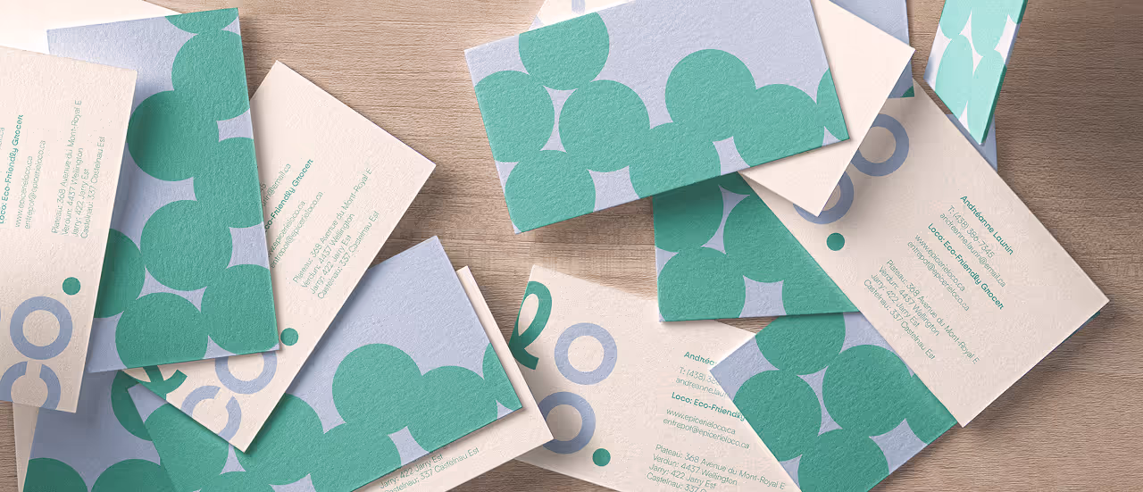 Scattered eco-friendly business cards with green circular patterns on a wooden surface.