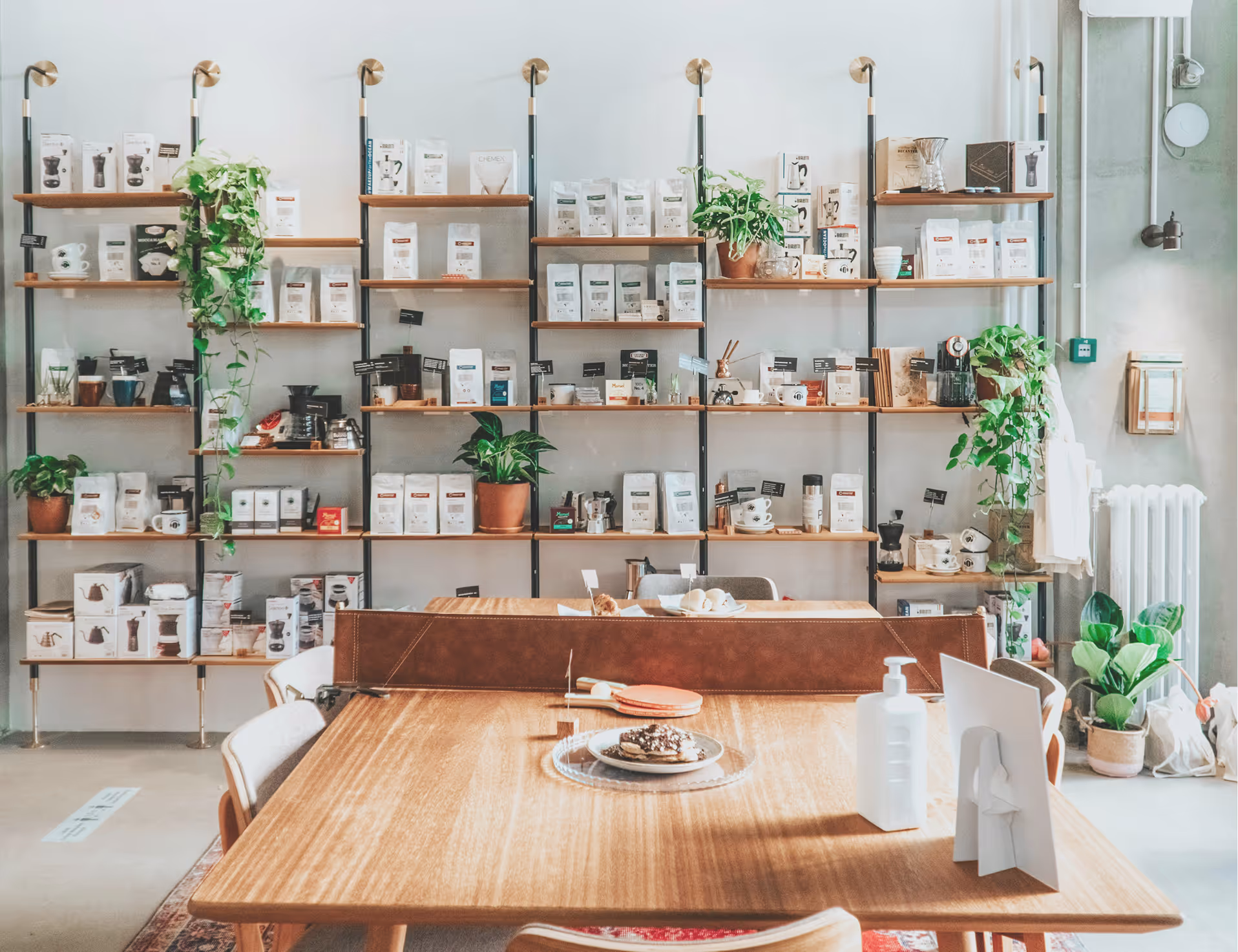 Modern coffee shop interior with wooden table, potted plants, and shelves filled with loco products.
