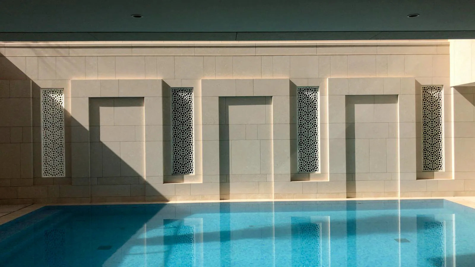 Backlit marble jali niches set into the pool wall at the Al Mula Residence, Kuwait