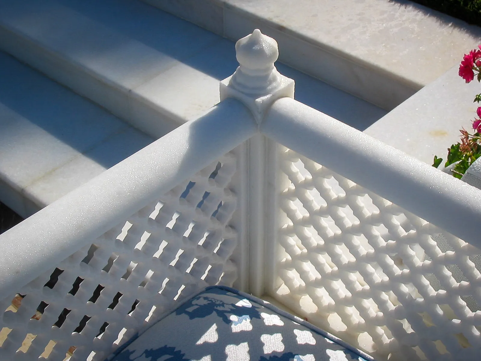 Close-up of a white marble poolside bench with a pierced jali backrest and lotus finial, The Los Altos Hills Estate, California