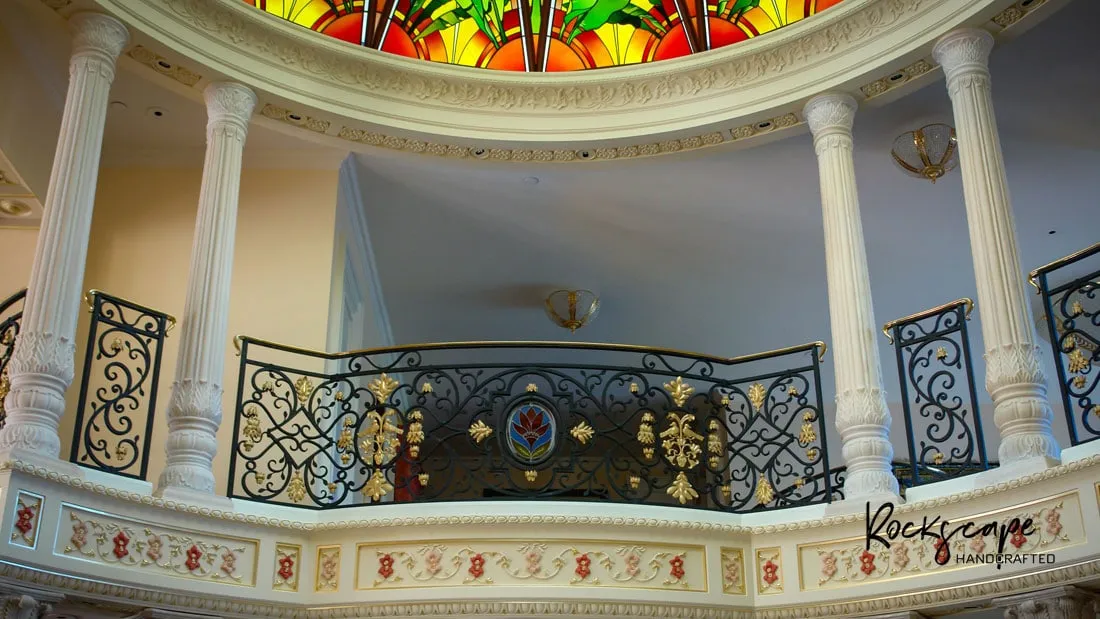 Domed rotunda with fluted marble columns, a wrought-iron gallery railing and a stained-glass ceiling