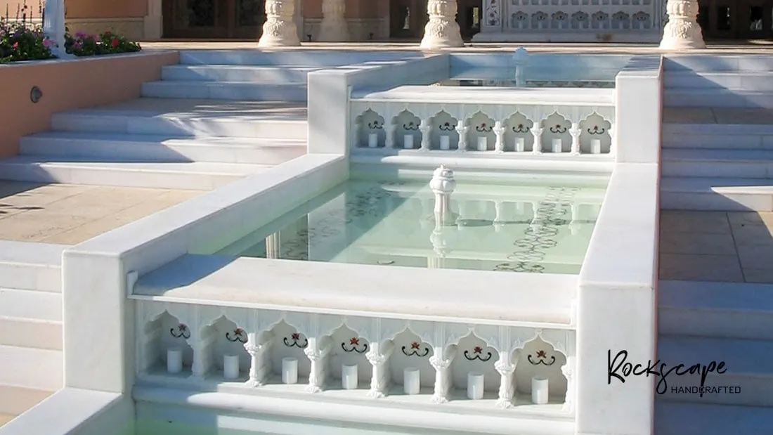White marble steps with jali balustrades descending beside a reflecting water channel