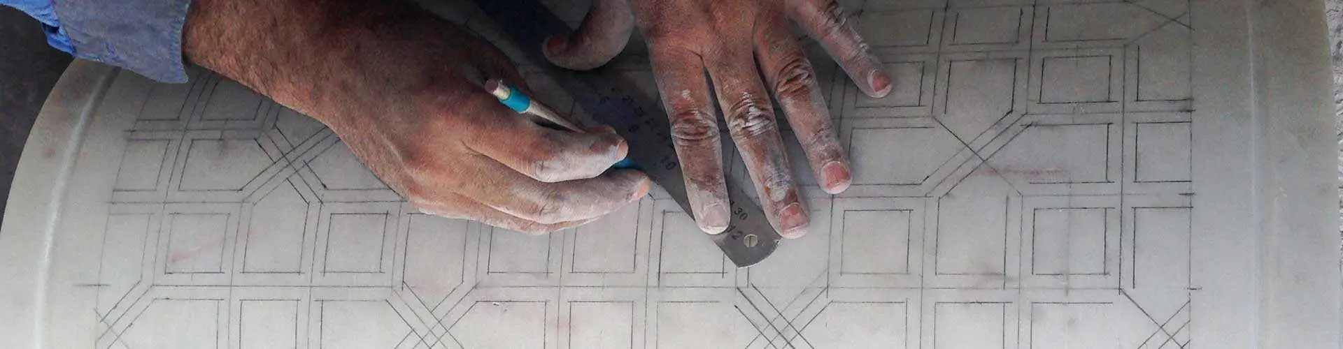 Designer's hands drafting a detailed stone carving pattern on paper
