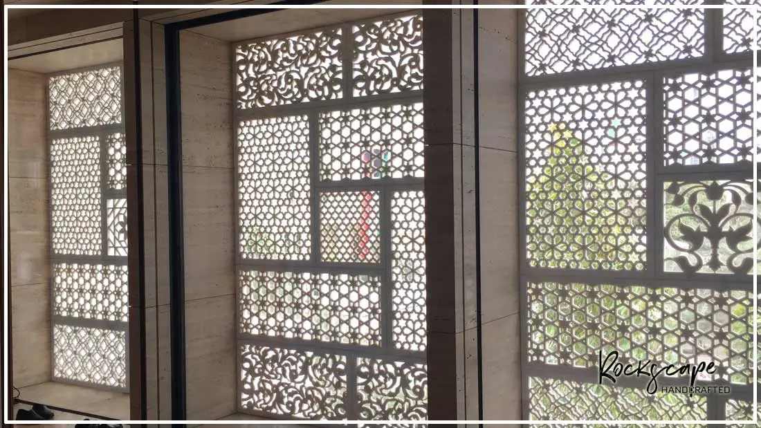 Carved stone jali screens with geometric and floral lattice set into a window wall