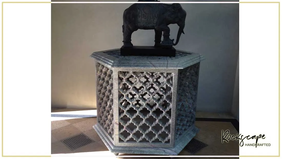 Hexagonal white marble jali pedestal topped with a black elephant sculpture
