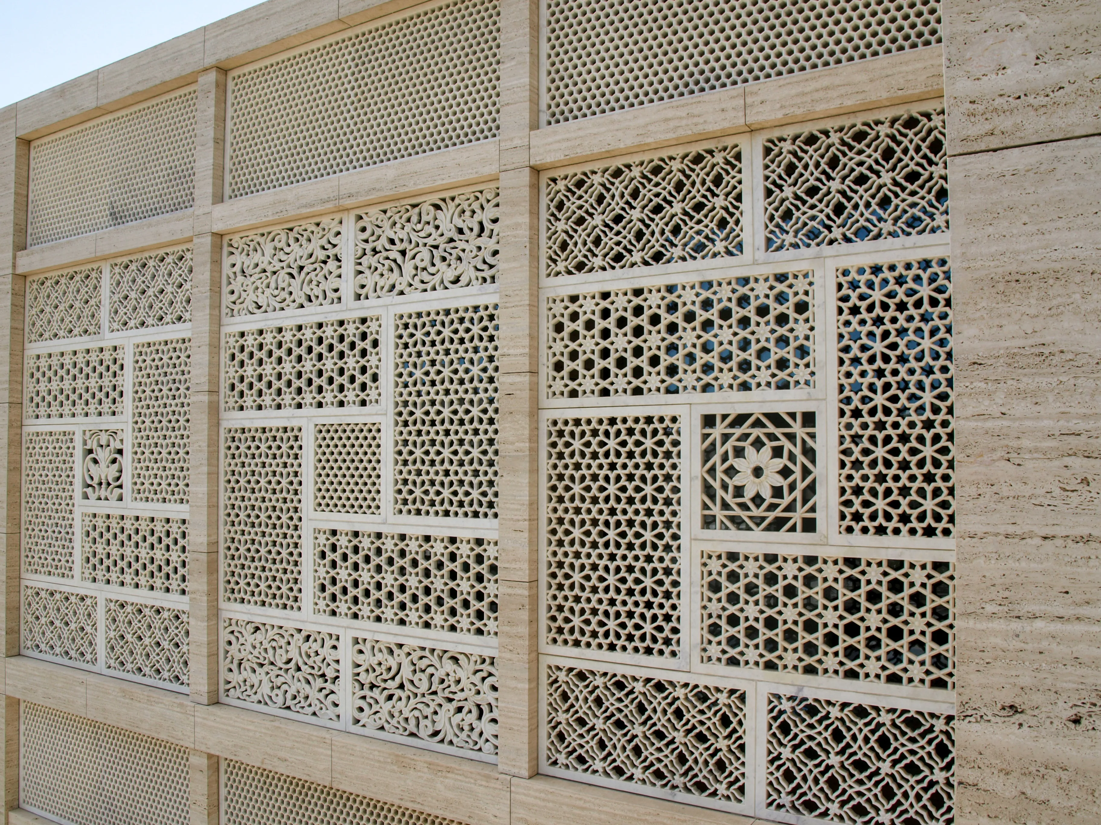 Geometric hand-carved stone mashrabiya panels across the facade of the Elite Residence, Kuwait