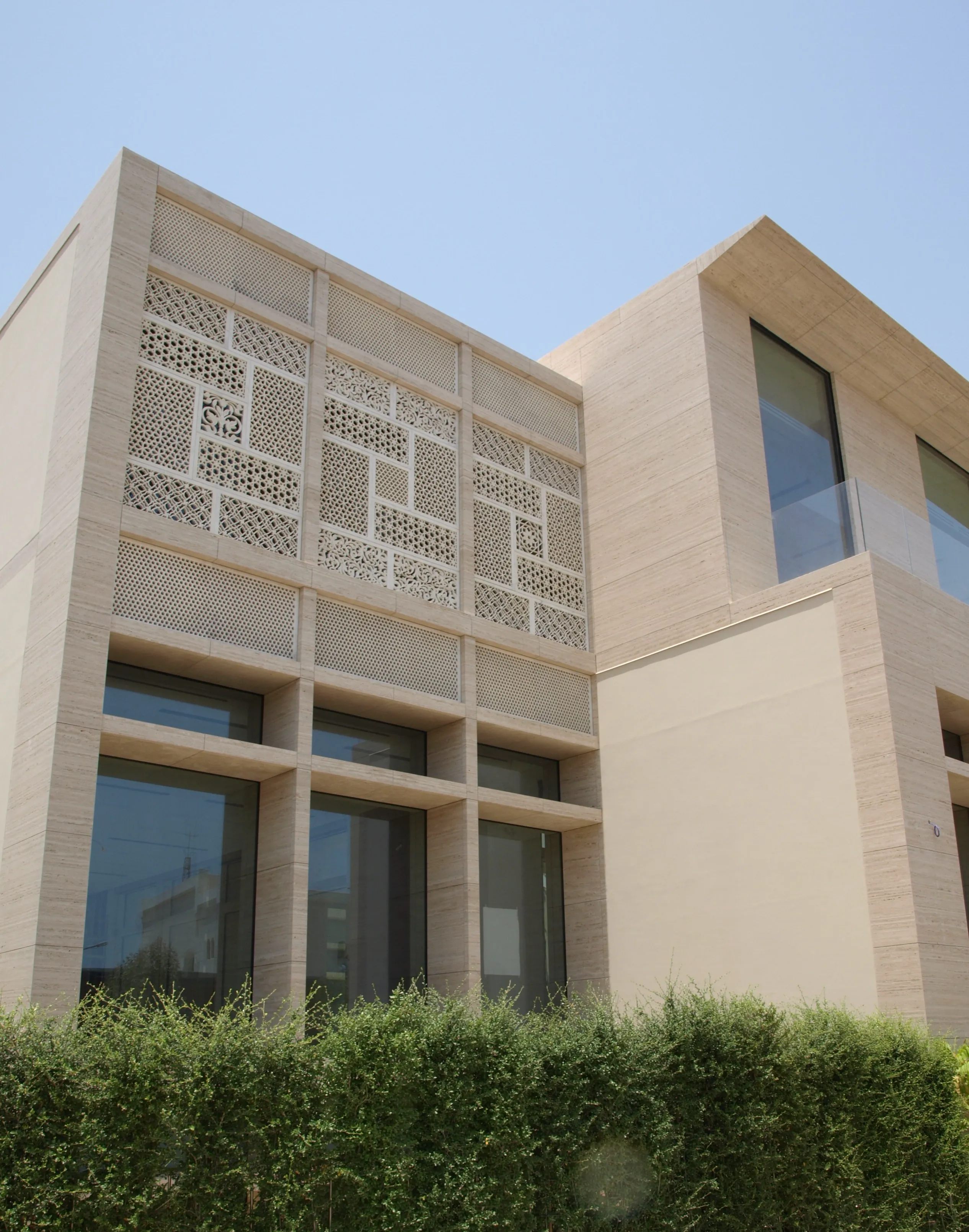 Modern facade of the Elite Residence, Kuwait, clad in carved stone mashrabiya panels above a hedge