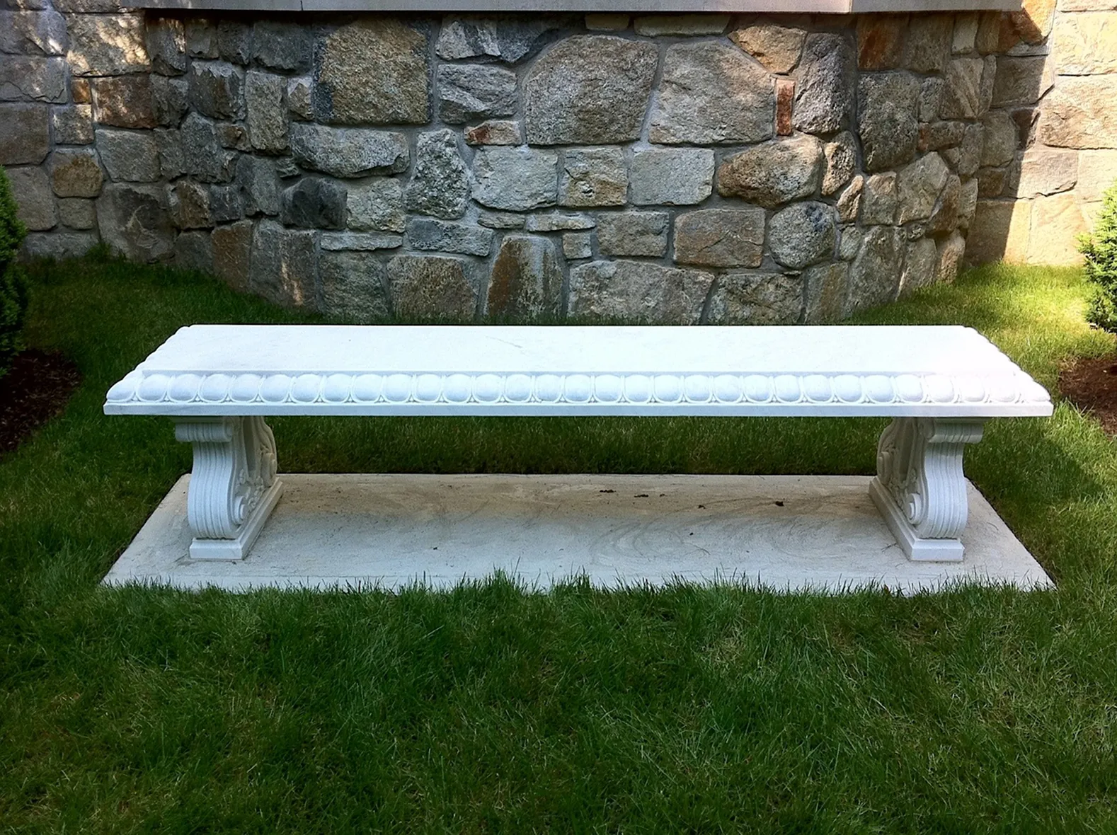 Simple white marble garden bench on the lawn beside a fieldstone wall, The Greenwich Estate