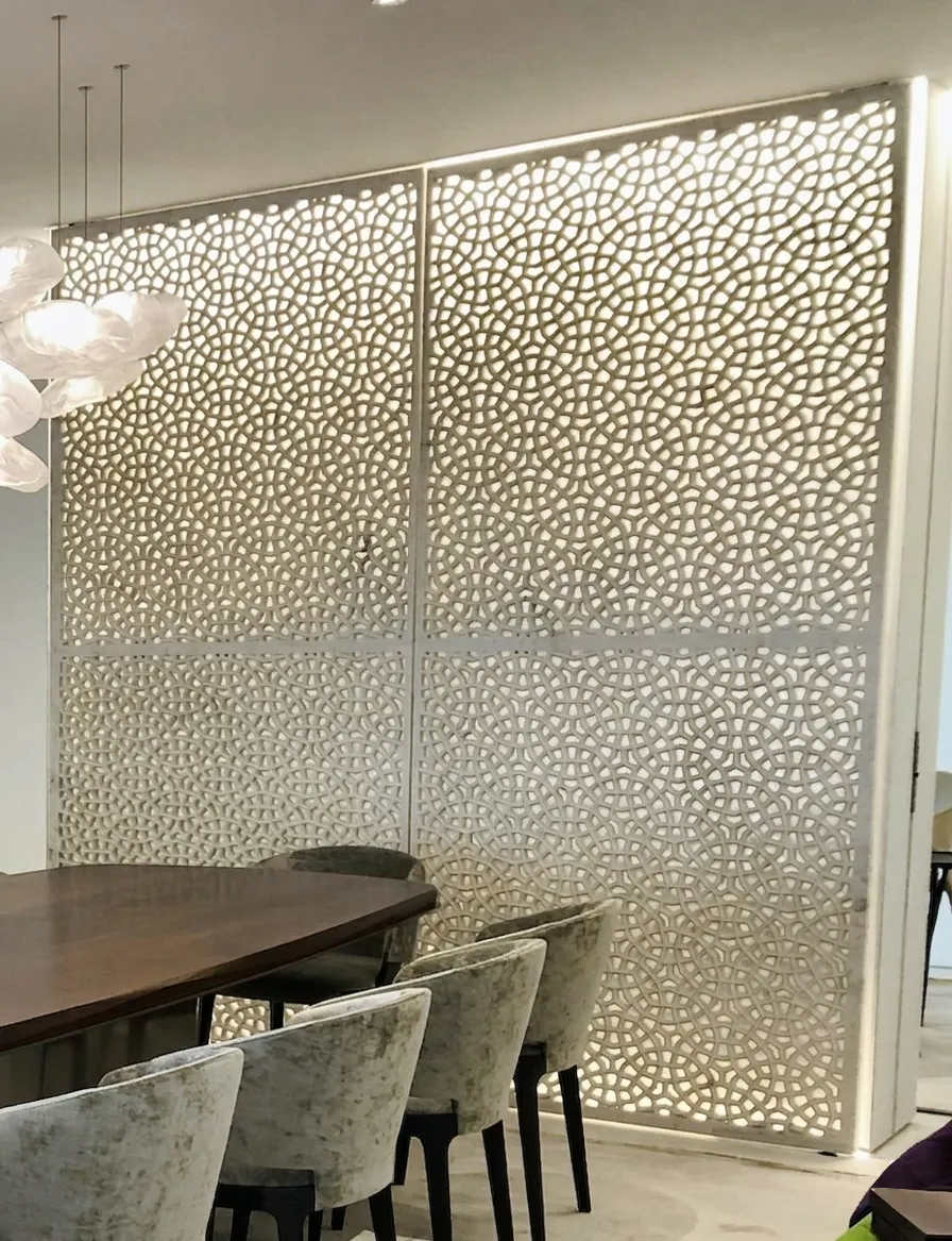Backlit Calacatta marble jali screen beside the dining table at The Plaza Residence, New York