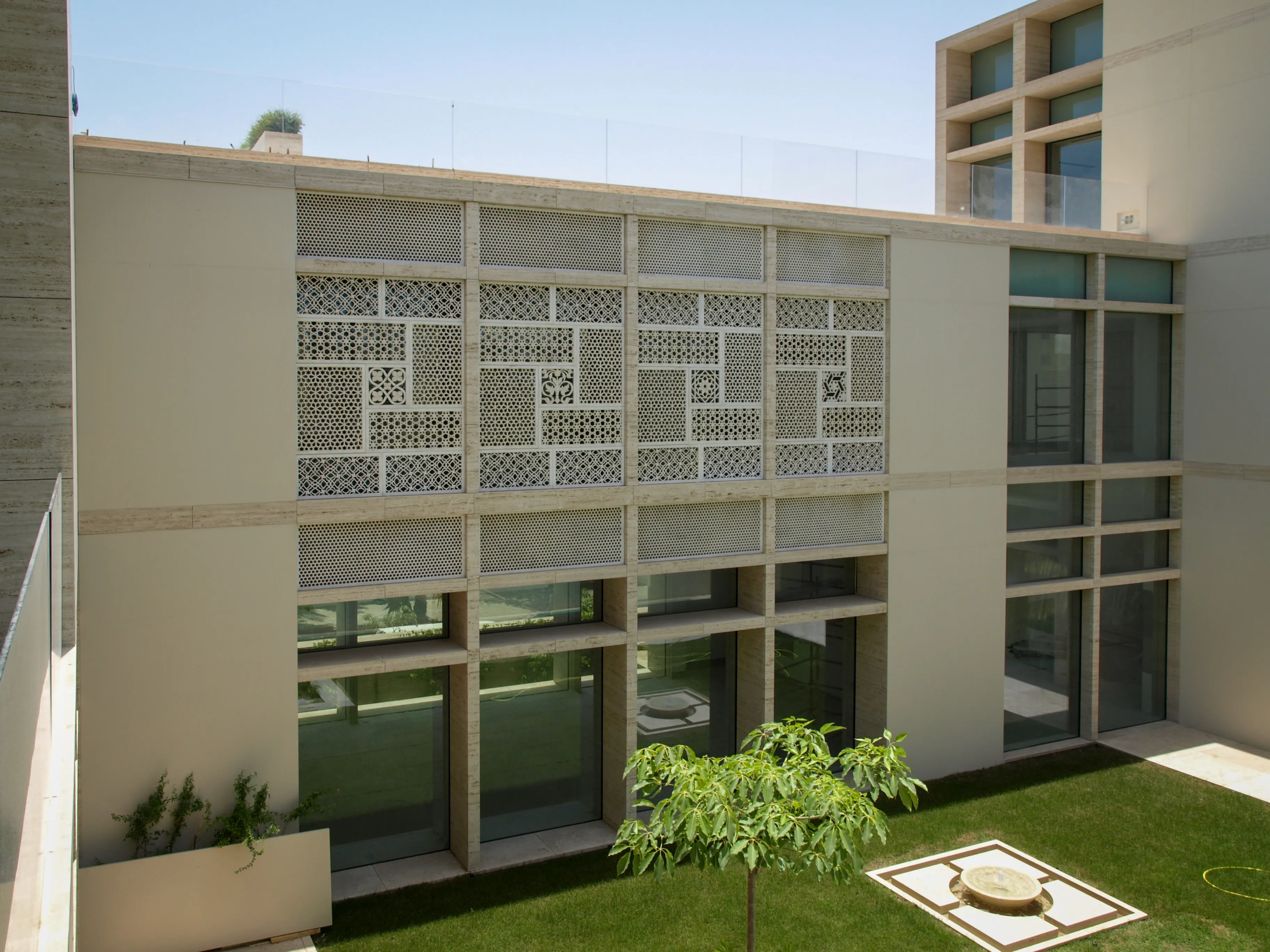 Courtyard lawn below the carved stone jali facade of the Elite Residence, Kuwait
