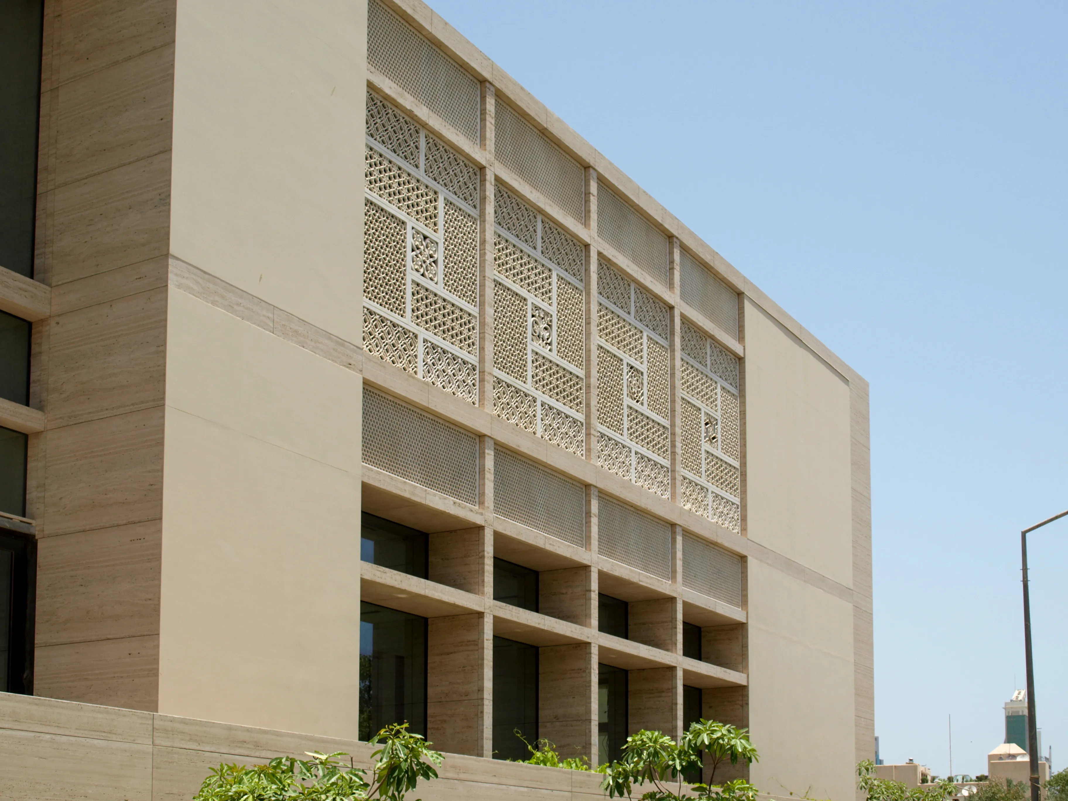 Corner view of the Elite Residence, Kuwait, showing carved stone jali panels above full-height windows