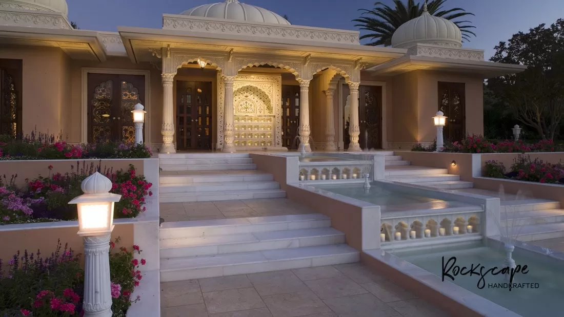 Marble villa with carved arches, domed chhatris and lit garden lanterns along the entrance steps at dusk