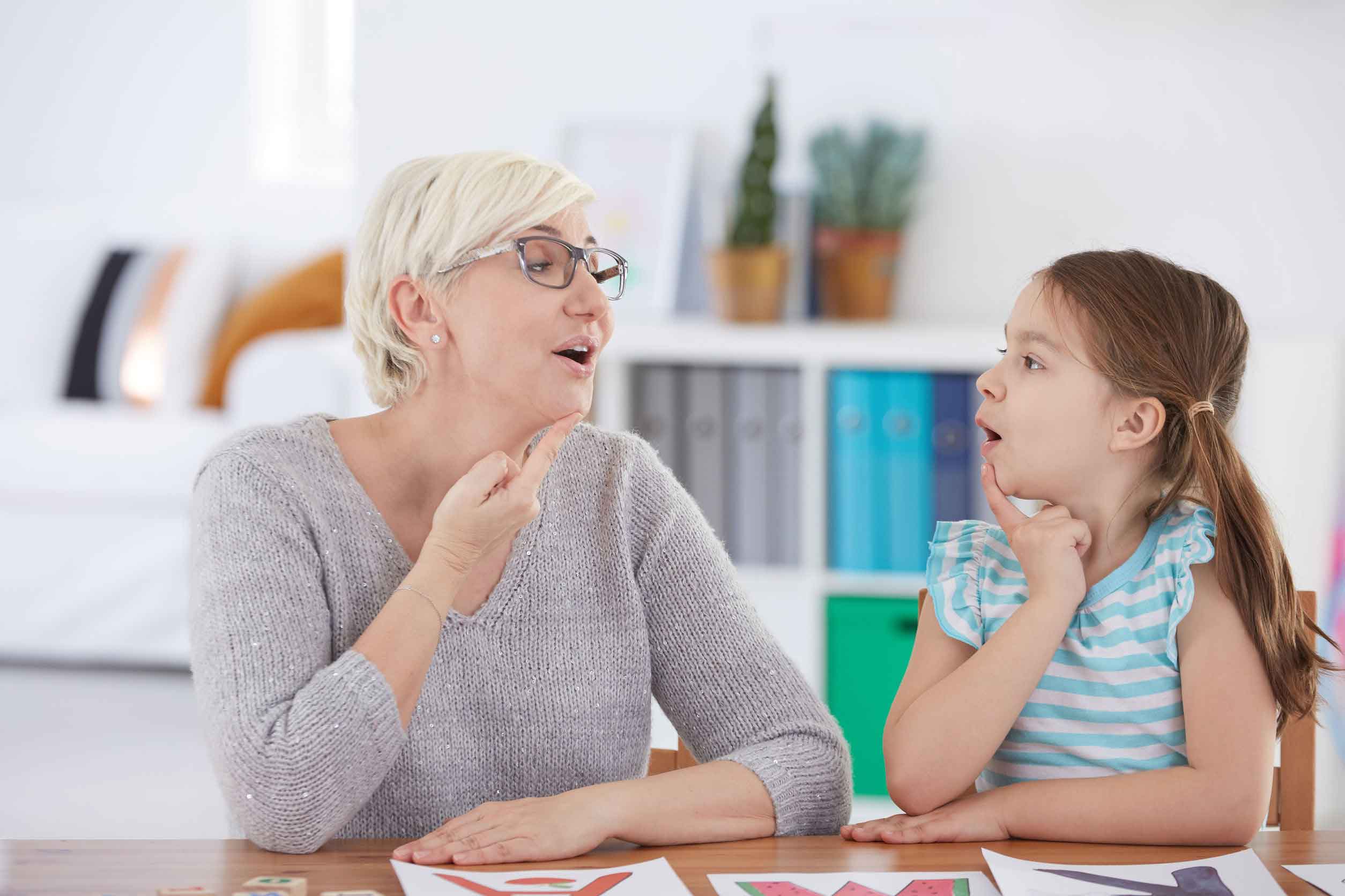 Child and speech pathologist practicing speaking techniques