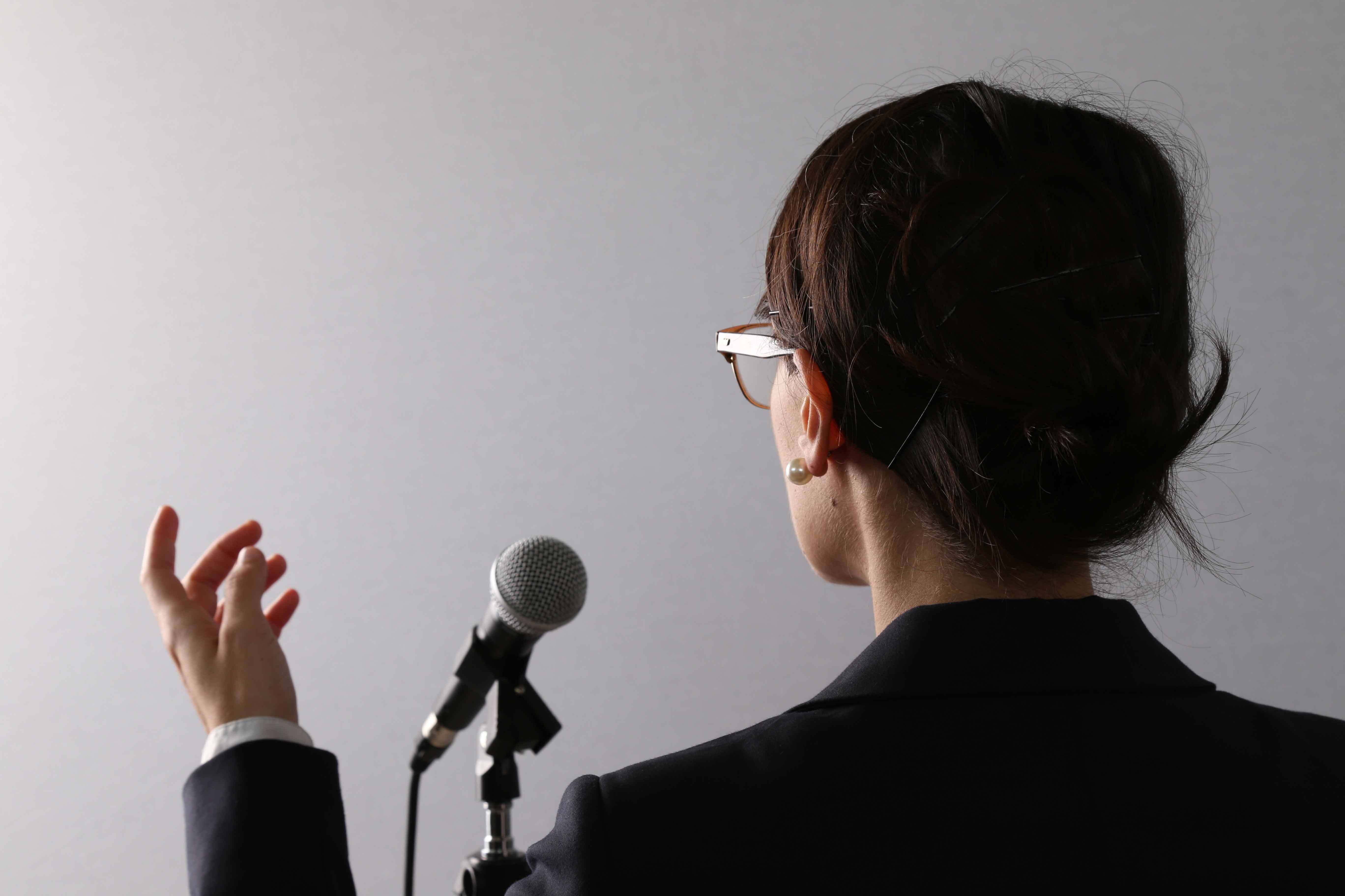 Woman speaking into a microphone|Mom and child meeting with speech pathologist