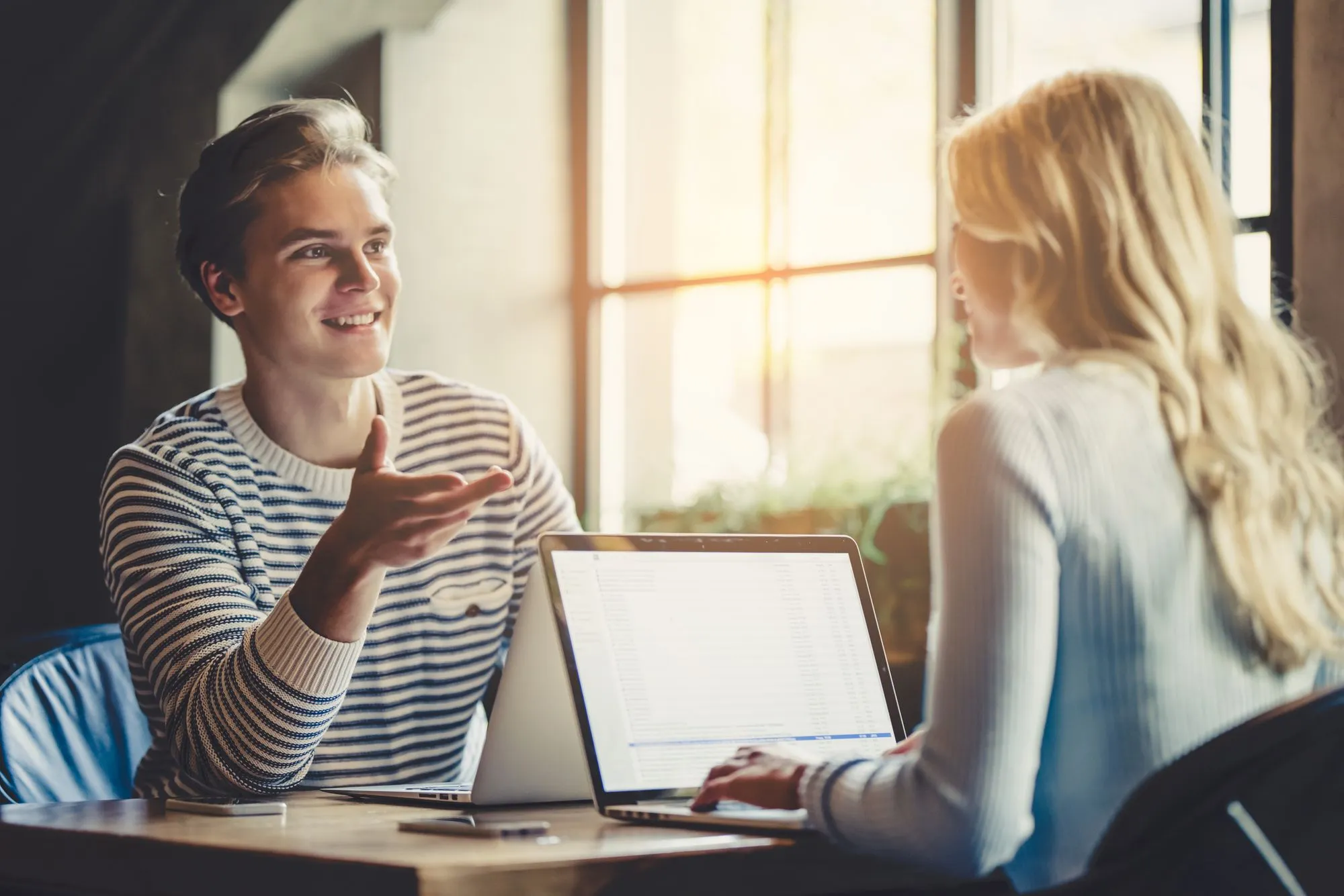 An adult man with stuttering talking confidently to a woman who is listening to him speak fluently because he's using an anti-stuttering device