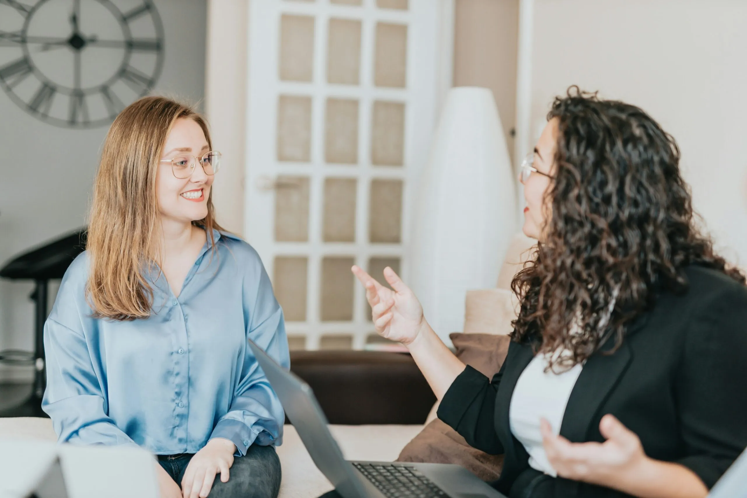 Two ladies speaking at a work meeting.|SpeechEasy's Comfort Fit anti-stuttering device.|SpeechEasy's Completely-in-Canal anti-stuttering device.|SpeechEasy's In-the-Canal anti-stuttering device.|SpeechEasy's Behind-the-Ear anti-stuttering device.