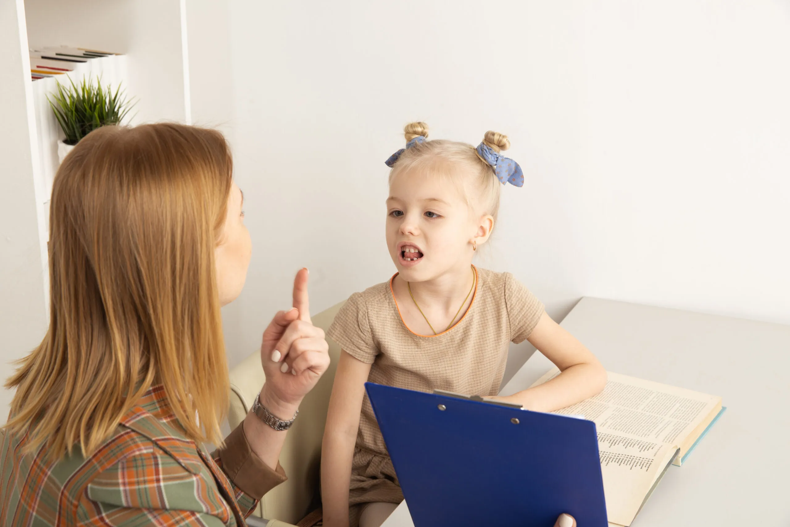 Girl with speech therapist in cabinet trainiing pronunciation