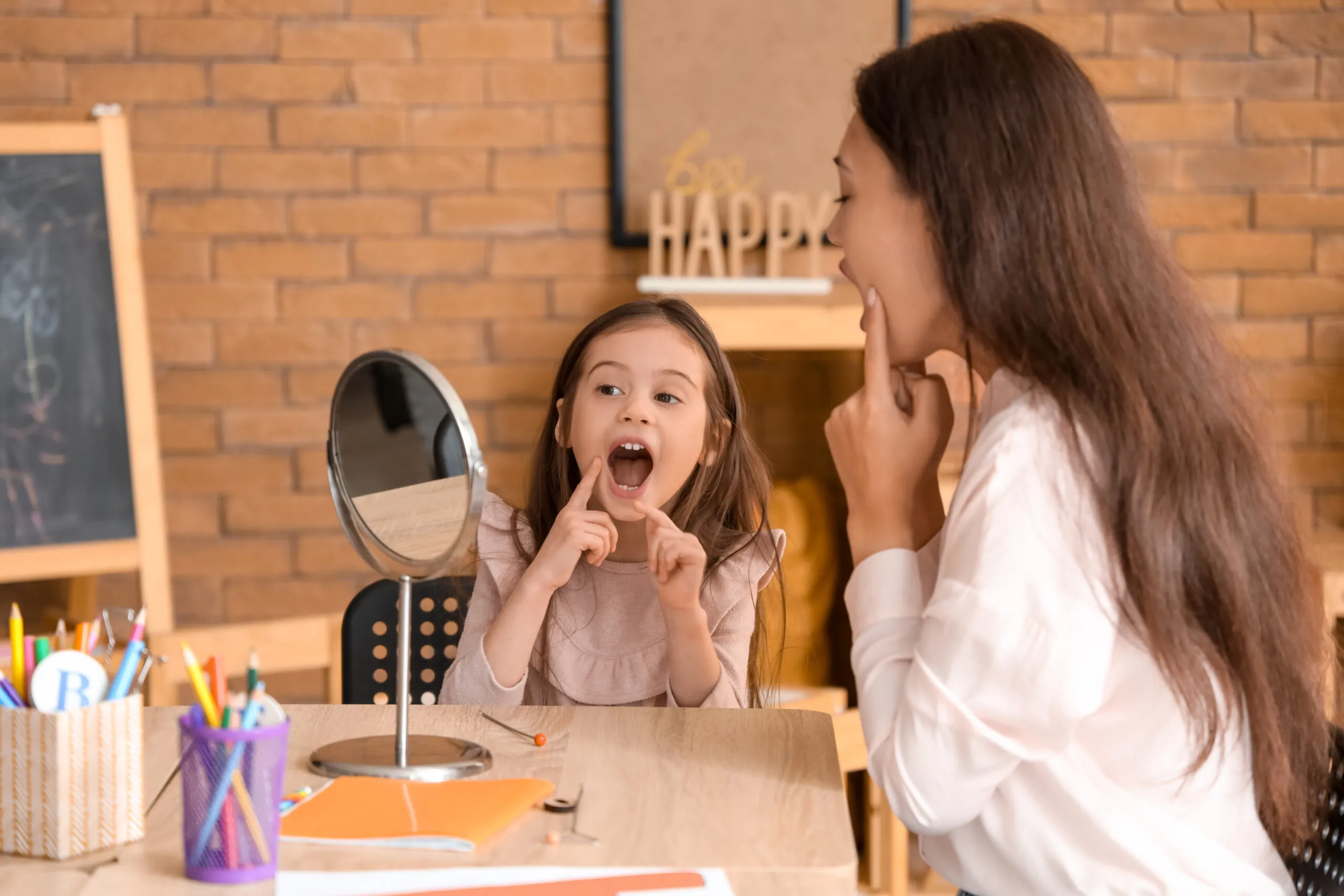 Female speech therapist working with little girl at table in office