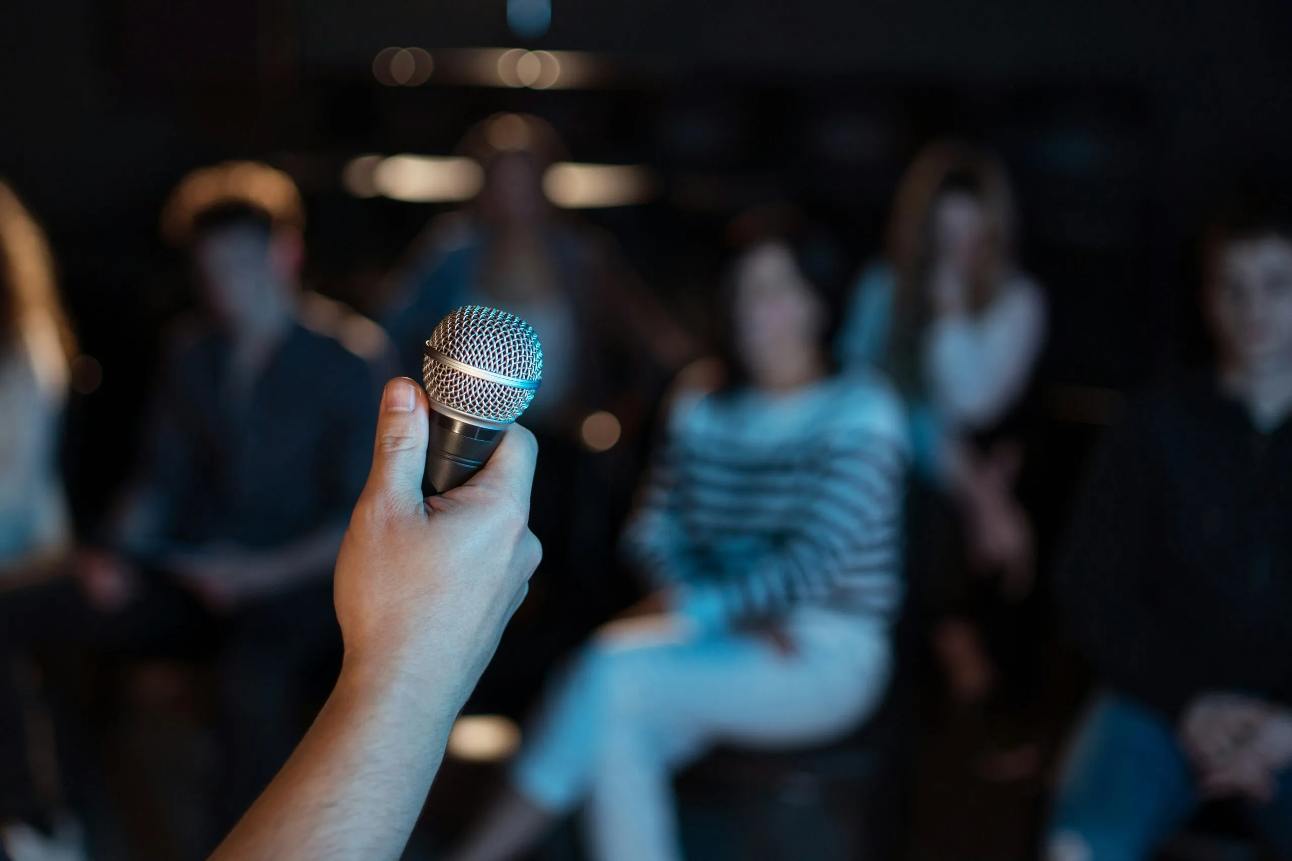 person holding a microphone infront of a crowd