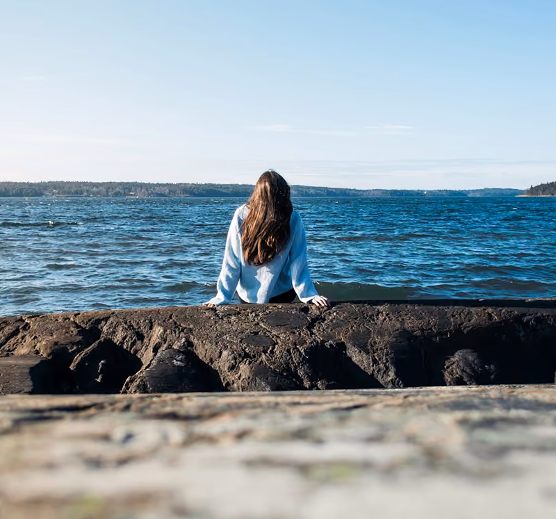 girl sitting next to the ocean