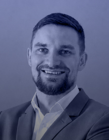 Smiling man with short hair and beard wearing a suit jacket and collared shirt.