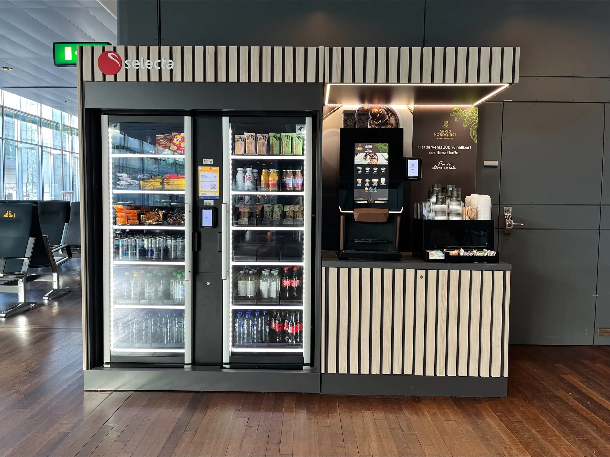 Selecta vending station with refrigerated snacks, drinks, and a coffee machine with cups and condiments.