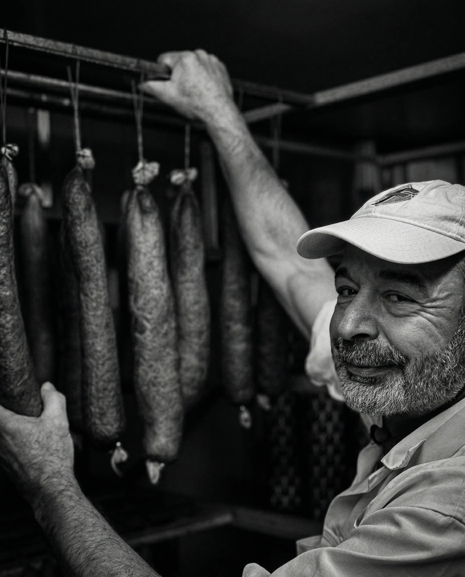 Fleischermeister mit gereiften Salami im Reiferaum