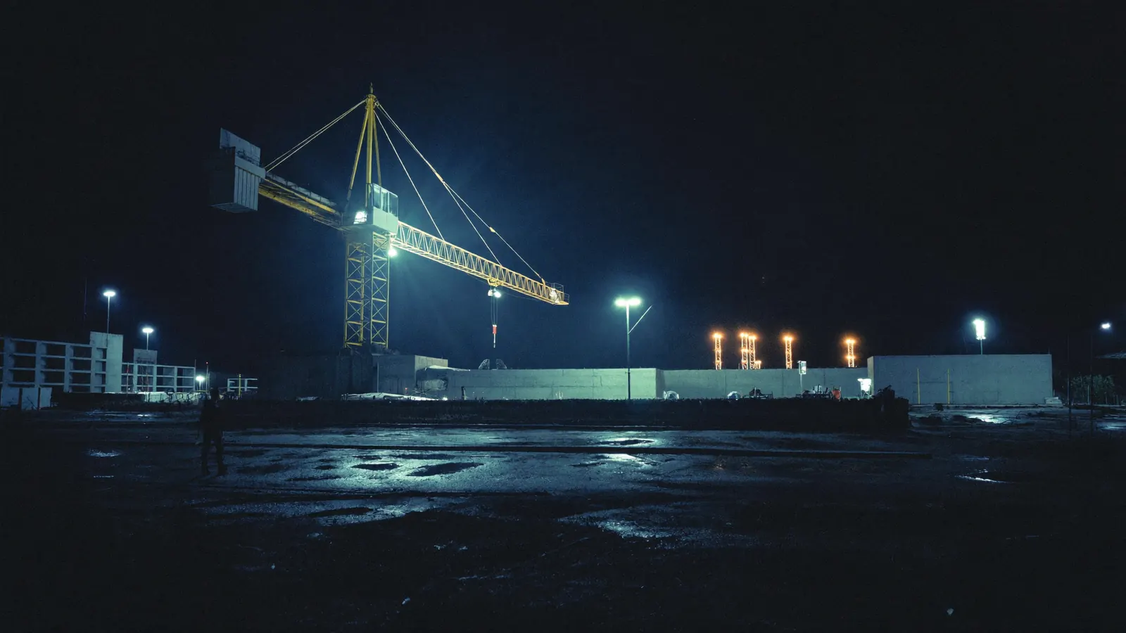 Tower crane under floodlights at a night construction site