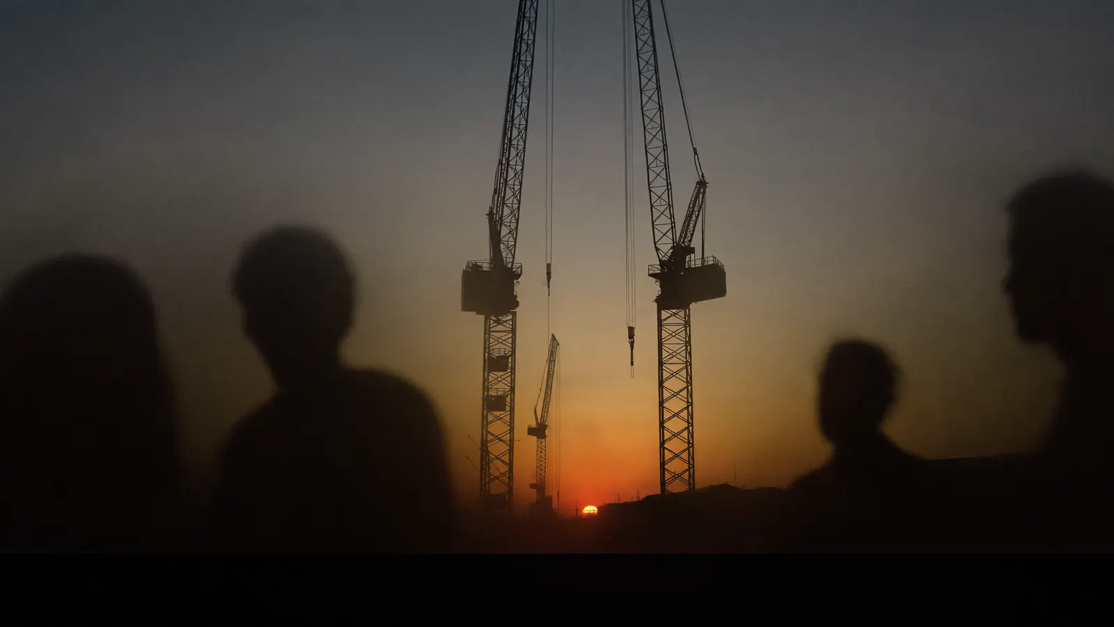 Quayside cranes silhouetted against a sunset sky