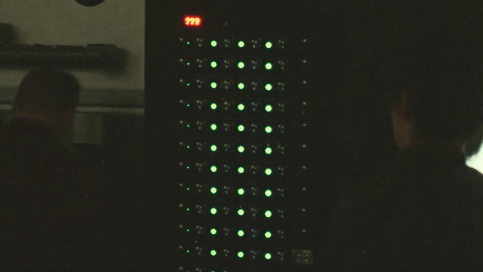 Rack of green indicator lights glowing in a dark equipment room
