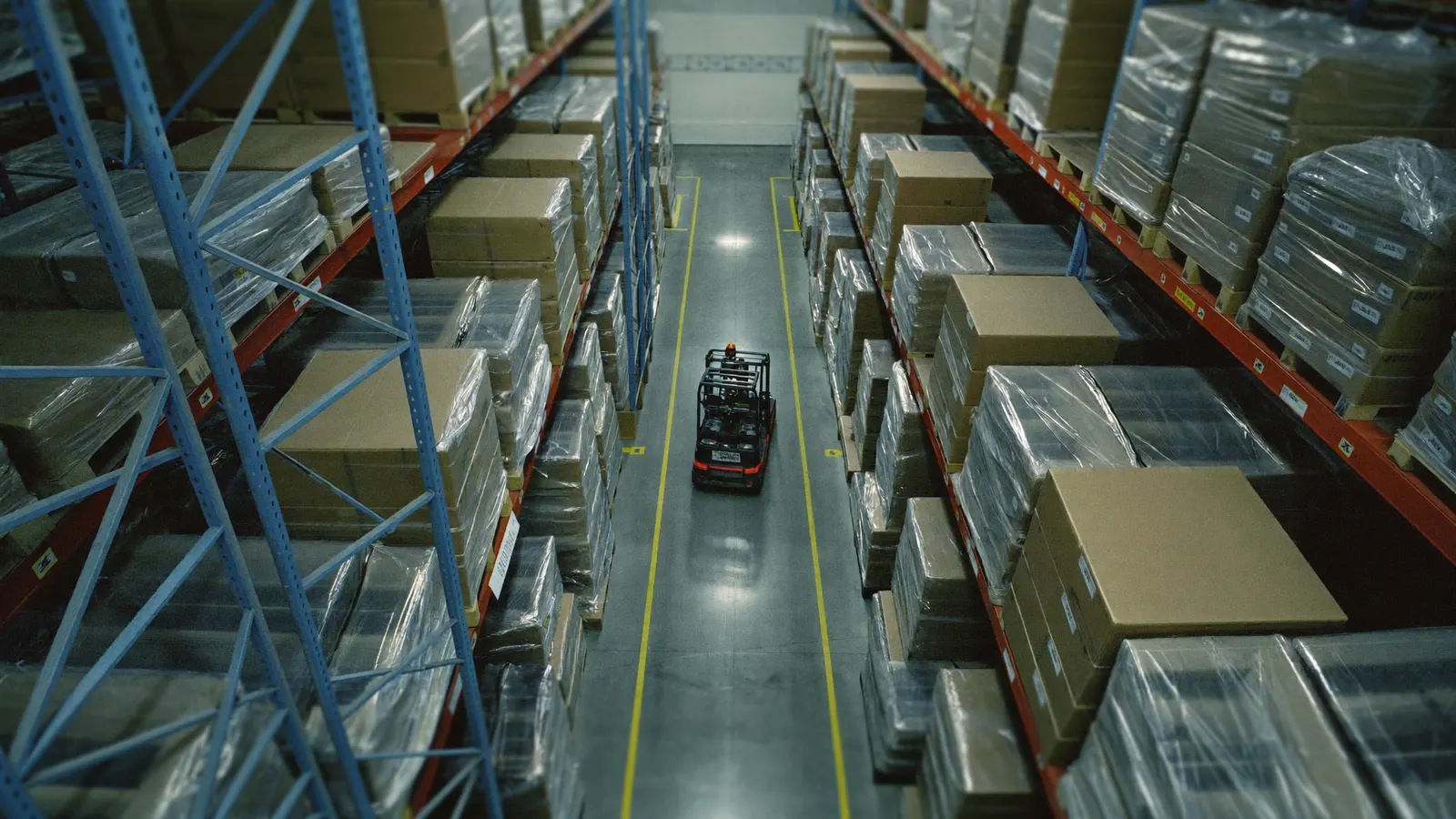 Overhead view of a forklift travelling a tall warehouse racking aisle