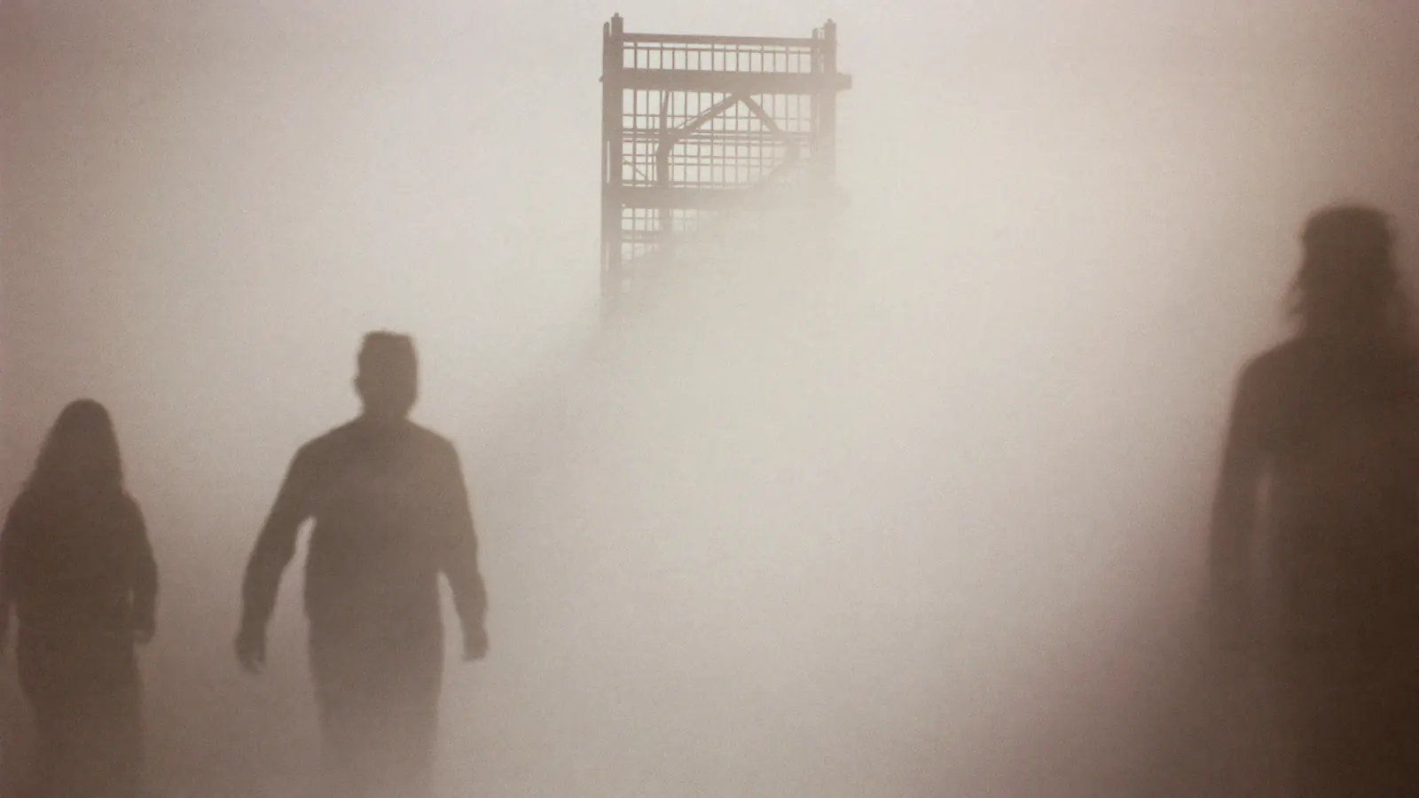 Industrial pipe structure and silhouetted figures in thick fog