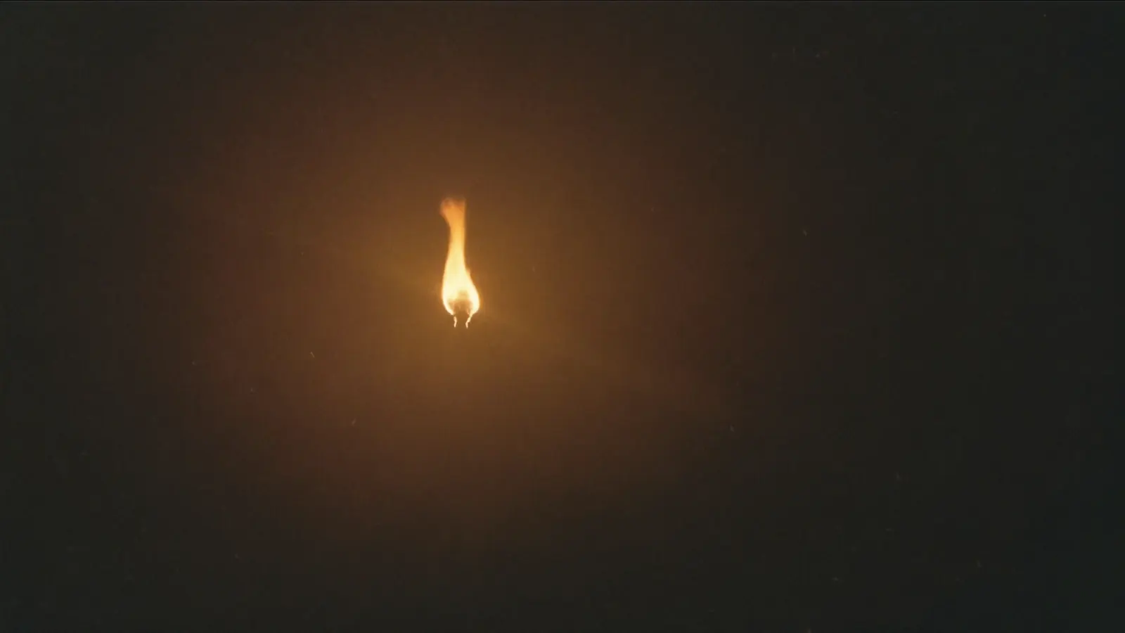 Distant flare burning against a dark night sky