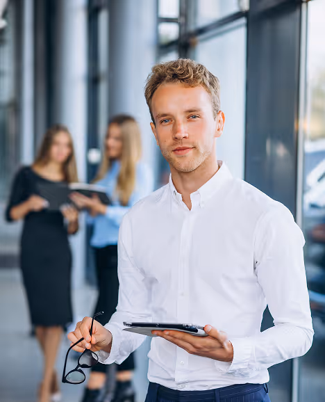 Jonge man in overhemd staat in kantoor met een tablet in zijn handen.