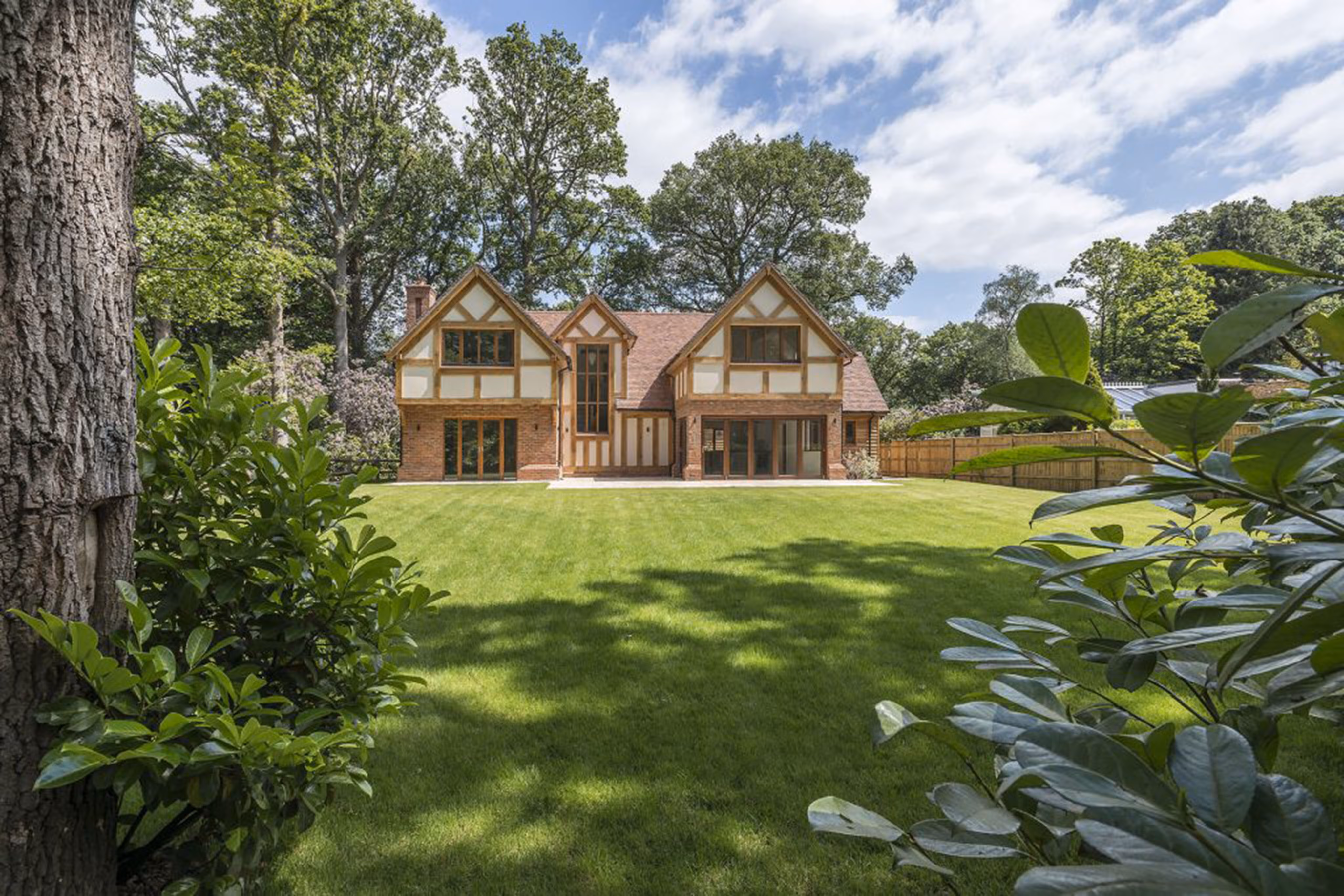A large country home on a sunny day with beautiful grass and a blue sky 