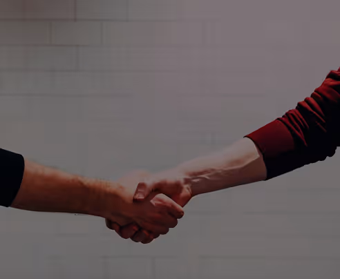Two people shaking hands against a plain tiled wall background.