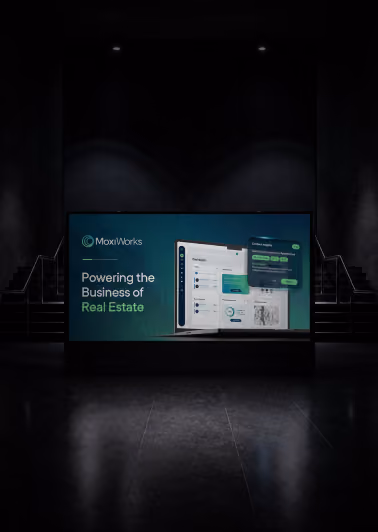 Dark hallway with illuminated advertisement for MoxiWorks showing a computer screen and text that reads 'Powering the Business of Real Estate.'